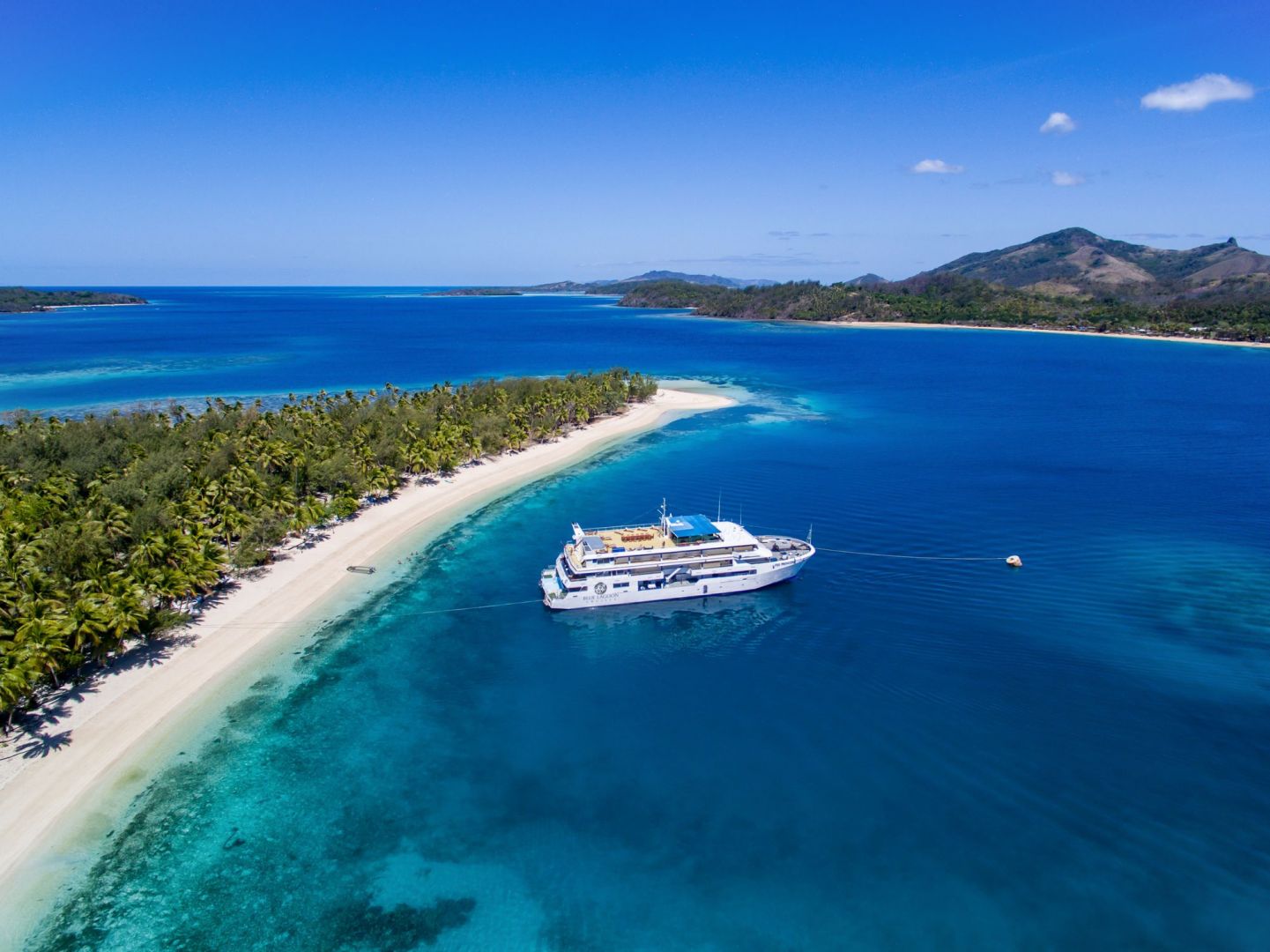 Blue Lagoon Cruise Ship moored in a beautiful Fijian lagoon with white sand beach