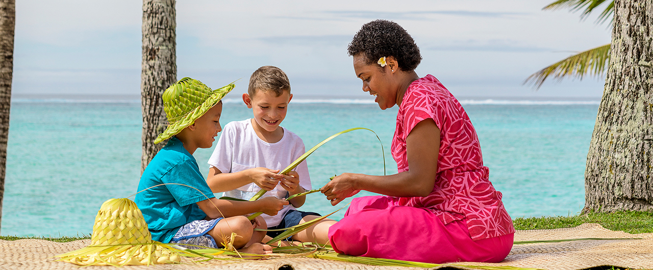 2 children with a Fijian Kids Club 'nanny' on the beach