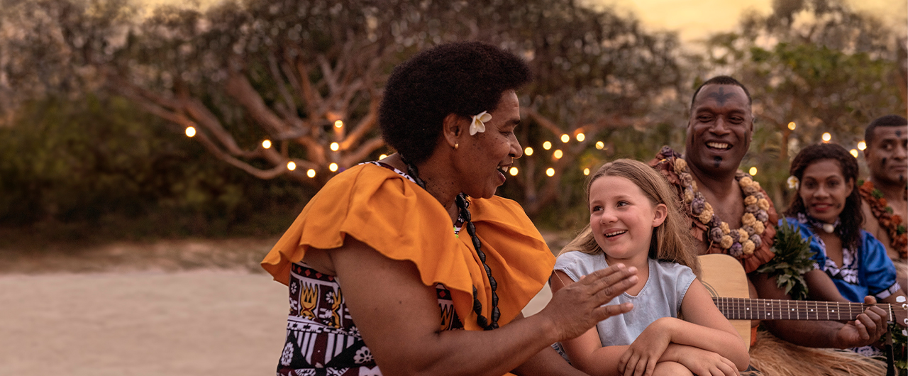 Fijian people singing on the beach with a girl