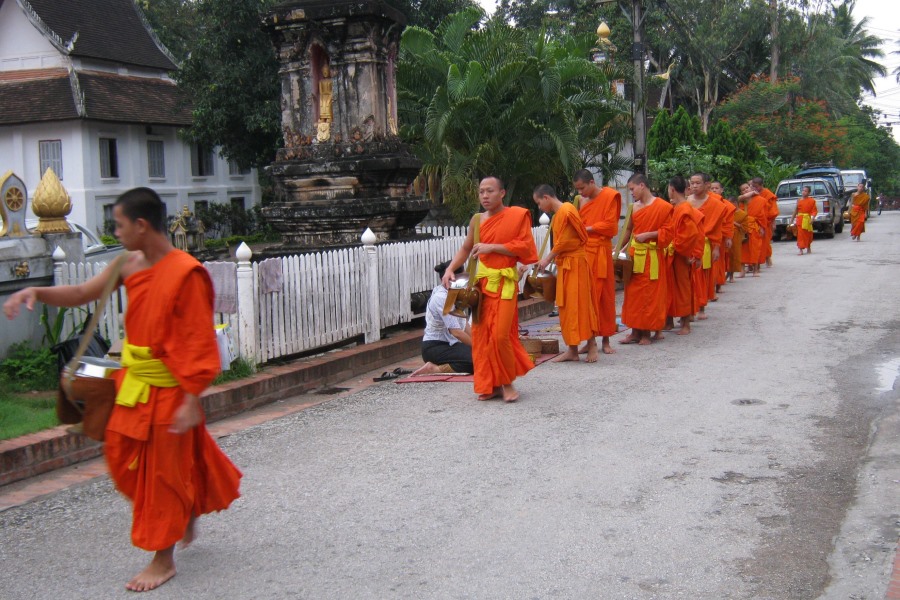 Buddhist monks in orange robes walking in a morning alms procession in Japan