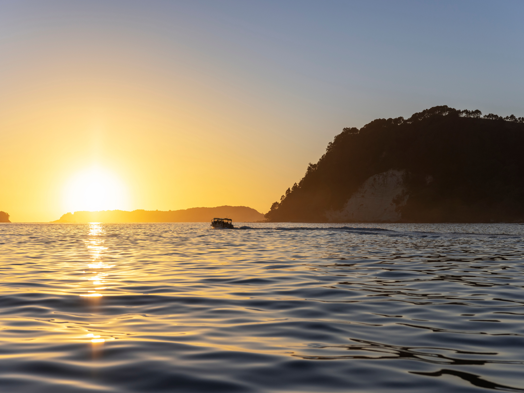 New Zealand coastal sunset Sunset over the ocean with coastline silhouette in New Zealand