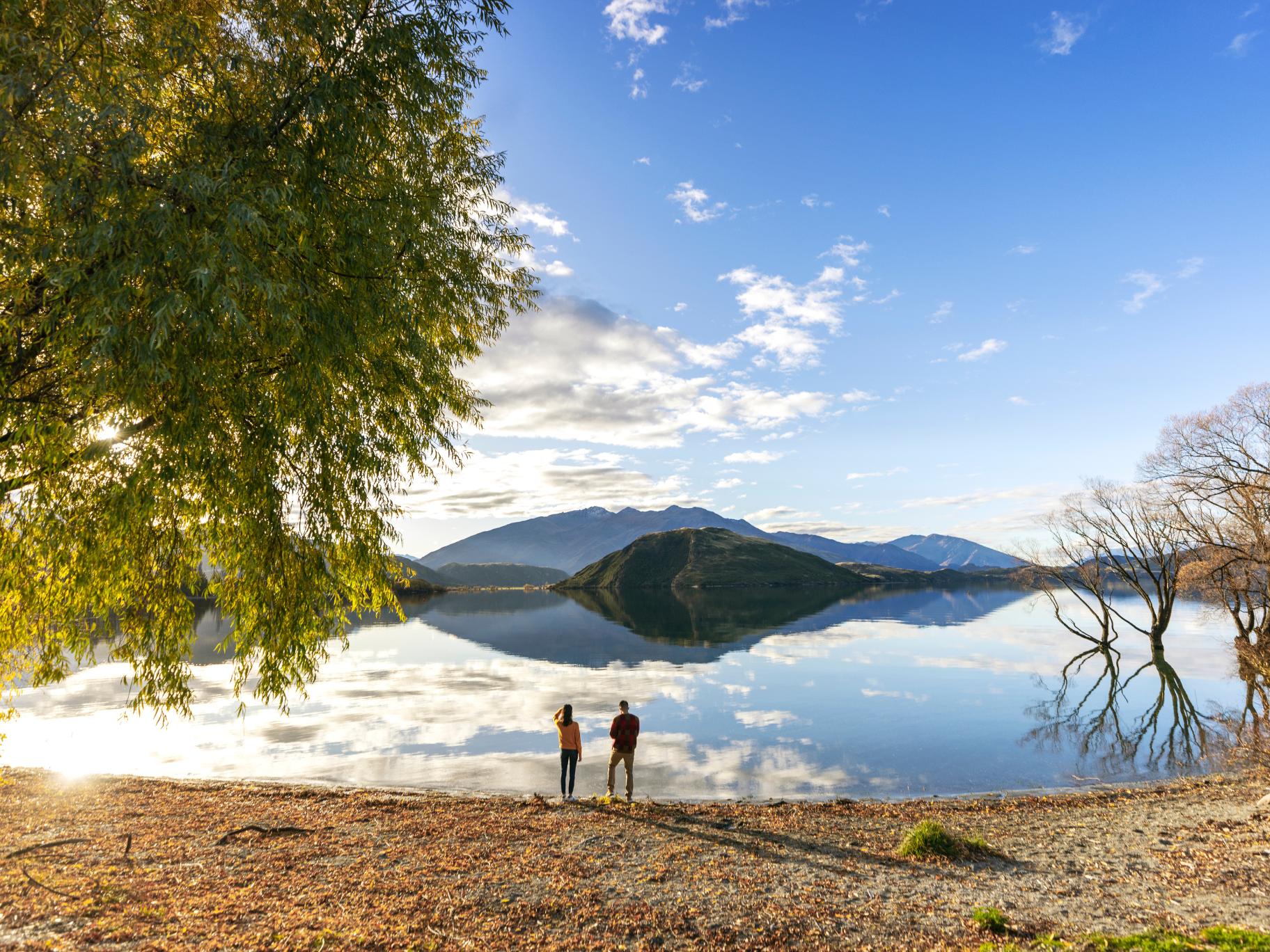 New Zealand South Island lake view Couple standing by a calm lake with mountain reflections in New Zealand South Island