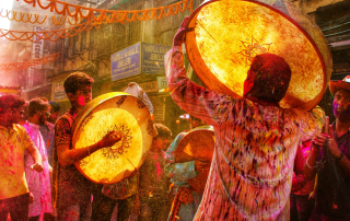 Festival drummers performing in a crowded street celebration surrounded by colour, music and energy