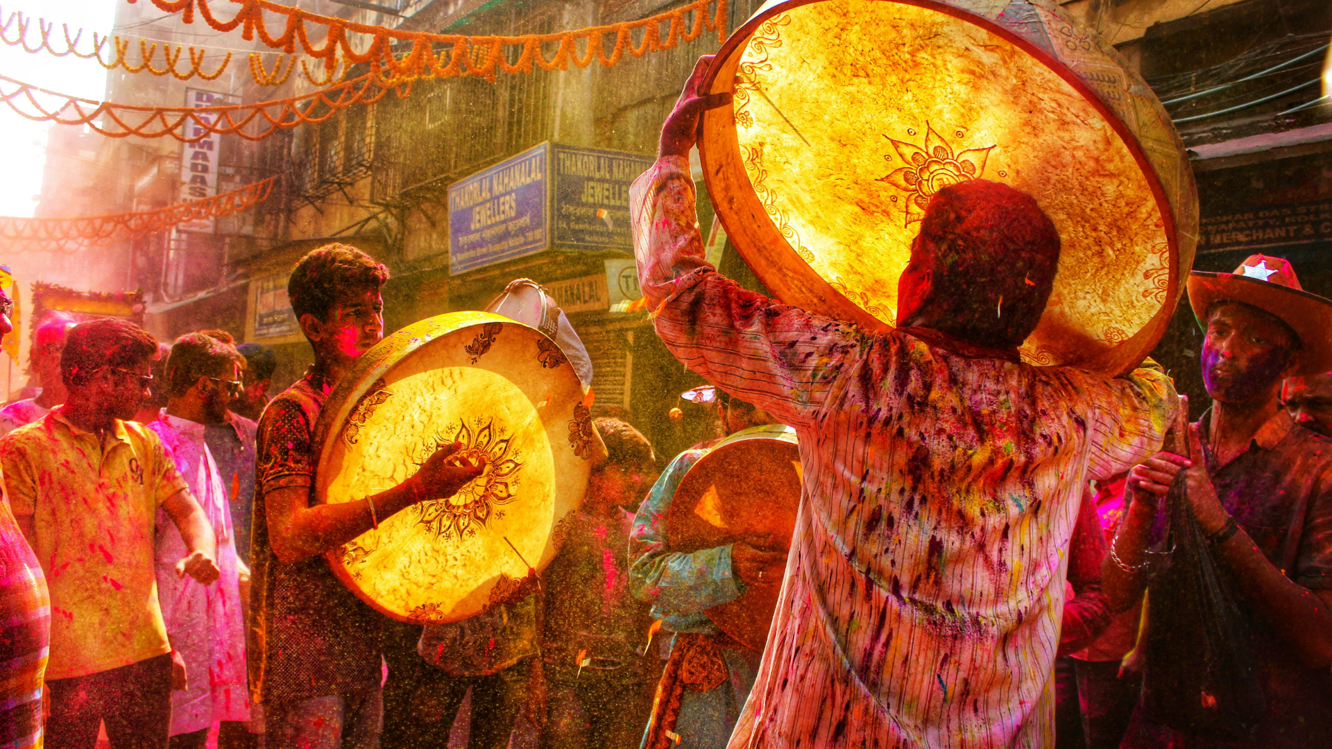 Festival drummers performing in a crowded street celebration surrounded by colour, music and energy