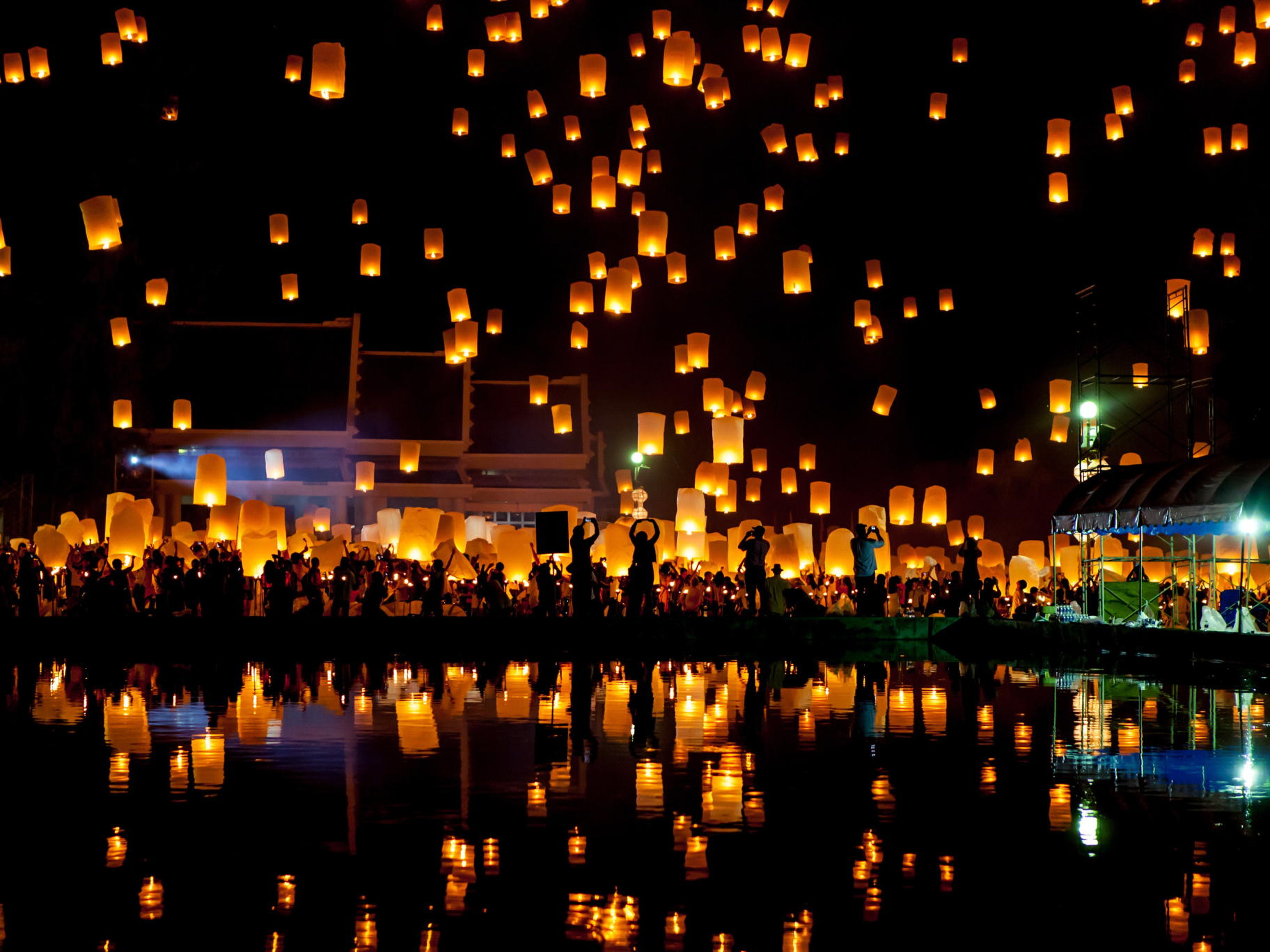 When The Atmosphere Takes Over Lanterns floating into the night sky above crowds gathered during a festival celebration