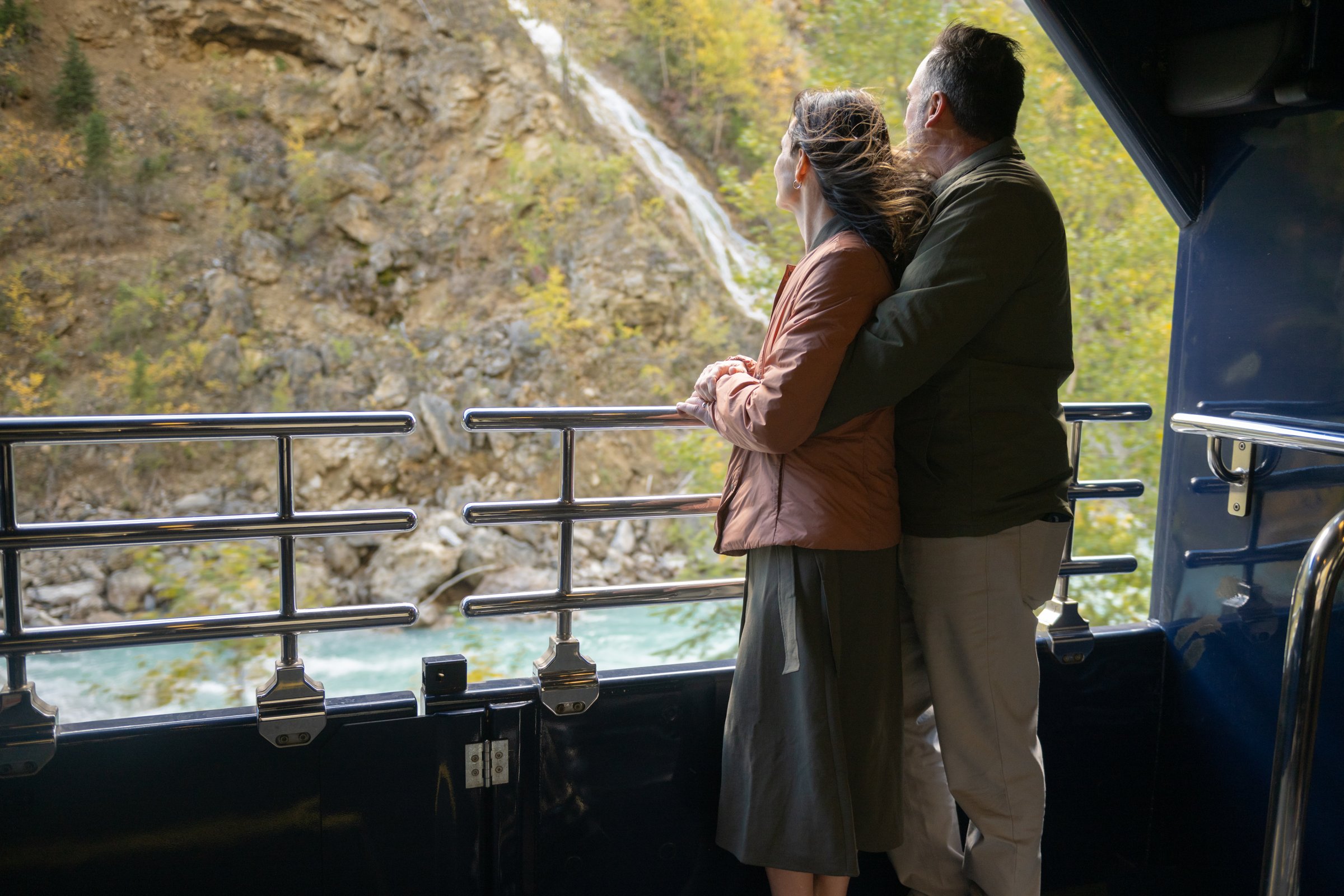 Couple enjoying the outdoor viewing platform on Rocky Mountaineer's GoldLeaf Service
